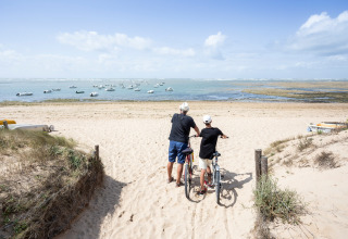 Twee personen met fietsen kijken uit over het strand bij Dolus d'Oléron, Nouvelle-Aquitaine, Frankrijk.
