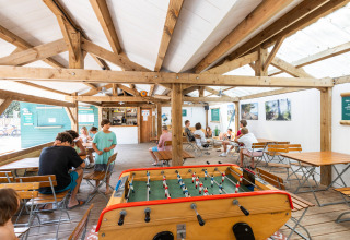 Gemeenschappelijke ruimte bij Huttopia Oléron Les Chênes Verts met tafelvoetbal en zitplaatsen.