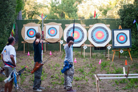 Tres personas practican tiro con arco en una pista al aire libre en Huttopia Oléron Les Chênes Verts, Francia.
