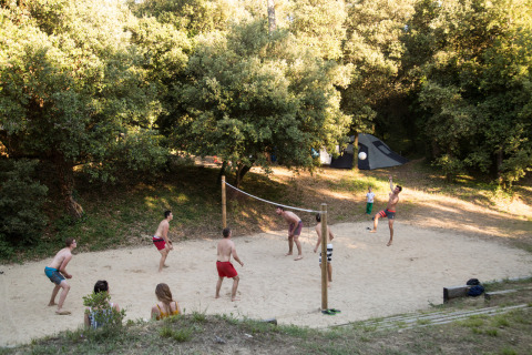 Huéspedes juegan al voleibol en la arena en Huttopia Oléron Les Chênes Verts, un parque vacacional en Francia.