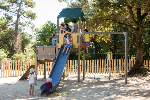 Niños jugando en un tobogán y estructura para trepar en Huttopia Oléron Les Chênes Verts, Nueva Aquitania, Francia.