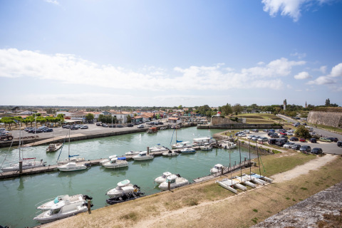 Zona portuaria con barcos y coches en Dolus d'Oleron, Nouvelle-Aquitania, Francia, bajo cielo despejado.