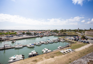 Havneområde med både og biler i Dolus d'Oleron, Nouvelle-Aquitaine, Frankrig, under blå himmel.
