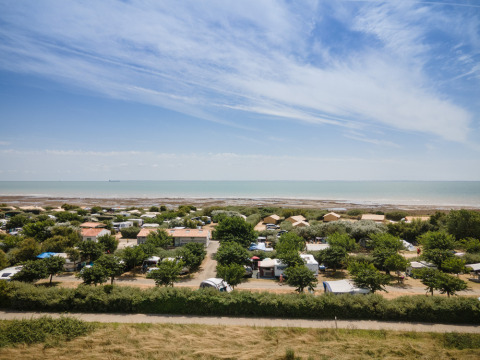 Vista panorámica del parque vacacional Huttopia Côte Sauvage en la costa de Nouvelle-Aquitania, Francia, con mar y cabañas.