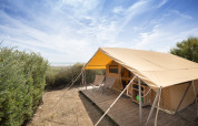 Tenda safari Bungalow Classic presso Huttopia Côte Sauvage in Francia, con sedie e terrazza in legno.