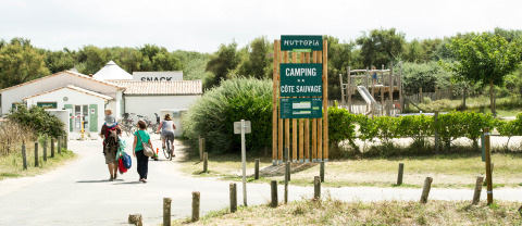Familias caminan y andan en bicicleta en la entrada del camping Huttopia Côte Sauvage en Nouvelle-Aquitaine, Francia.