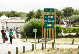 Familier går og cykler ved indgangen til Huttopia Côte Sauvage campingplads i Nouvelle-Aquitaine, Frankrig.