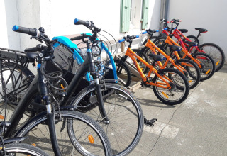 Flere farverige cykler, klar til udlejning, står opstillet ved siden af hinanden på Huttopia Côte Sauvage.