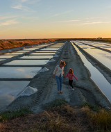 Mother and daughter walk along traditional salt flats at sunset near Sainte-Marie-de-Ré, France.