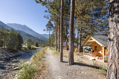Accogliente baita di legno lungo un sentiero fluviale a Huttopia la Clarée, Provenza-Alpi-Costa Azzurra, Francia.