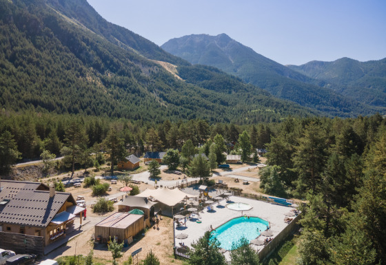 Parque vacacional Huttopia la Clarée en Provence-Alpes-Côte d’Azur, Francia, con piscina y vistas a las montañas.