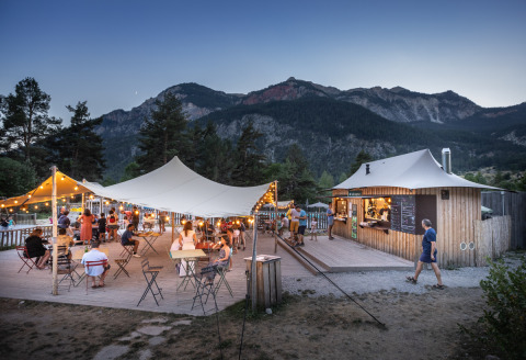 Espace de restauration extérieur au Huttopia la Clarée, ambiance conviviale sous tente, montagnes en Provence.