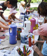 Niños y adultos hacen manualidades en una mesa al aire libre en el parque de vacaciones Huttopia la Clarée, Francia.