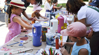 Niños y adultos hacen manualidades en una mesa al aire libre en el parque de vacaciones Huttopia la Clarée, Francia.