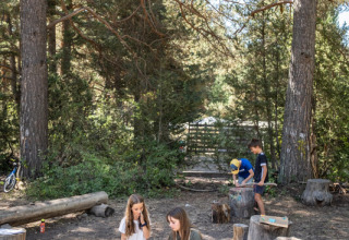 Des enfants font des activités créatives en plein air sous de grands arbres à Huttopia la Clarée, Provence-Alpes-Côte d’Azur, France.