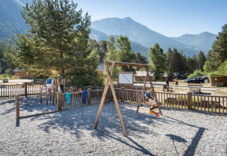 Børn leger på en legeplads med gynger i et ferieanlæg ved foden af bjerge i Provence-Alpes-Côte d’Azur, Frankrig.