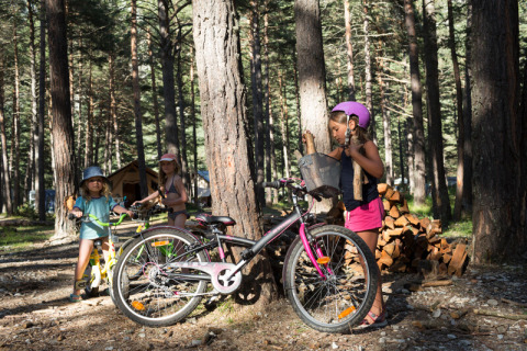 Niños juegan y montan en bicicleta en el bosque del parque vacacional Huttopia la Clarée en Provence-Alpes-Côte d’Azur, Francia.