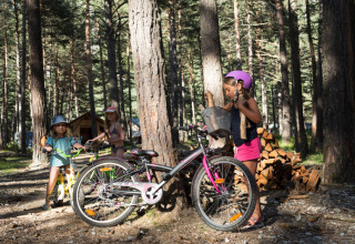 Kinderen spelen en fietsen in het bos bij Huttopia la Clarée vakantiepark in Provence-Alpes-Côte d’Azur, Frankrijk.