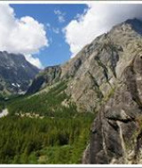 Escalador ascendiendo una roca con vista a montañas y valle cerca de Val-Des-Près, en Provence-Alpes-Côte d’Azur, Francia.