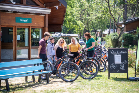 Gasten bij Camping La Pinède in Excenevex krijgen uitleg over elektrische fietsen bij de receptie.