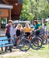Huéspedes en Camping La Pinède en Excenevex reciben una introducción a bicicletas eléctricas afuera.
