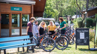 Huéspedes en Camping La Pinède en Excenevex reciben una introducción a bicicletas eléctricas afuera.