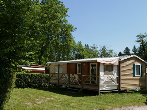 Mobil-home avec terrasse aménagée entouré de verdure au Camping La Pinède, Excenevex, Auvergne-Rhône-Alpes.