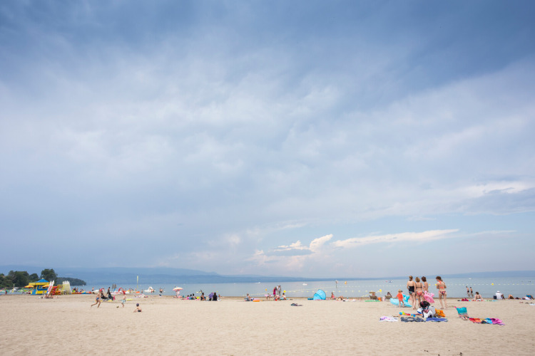 Beach scene at Camping La Pinède - Excenevex holiday park in Auvergne-Rhône-Alpes, France, with visitors.