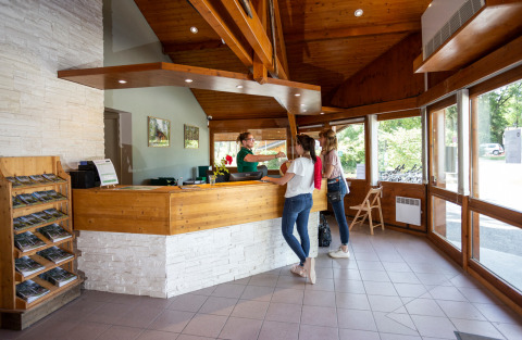 To gæster tjekker ind i receptionen på Camping La Pinède - Excenevex i Auvergne-Rhône-Alpes, Frankrig.