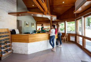 Zwei Gäste checken an der Rezeption von Camping La Pinède - Excenevex in Auvergne-Rhône-Alpes, Frankreich ein.
