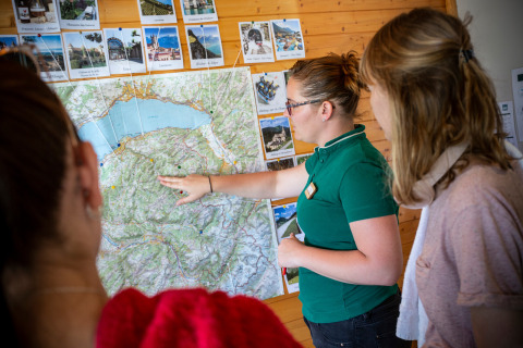 Una guía en Camping La Pinède - Excenevex, Auvergne-Rhône-Alpes, Francia, muestra el mapa a los visitantes.