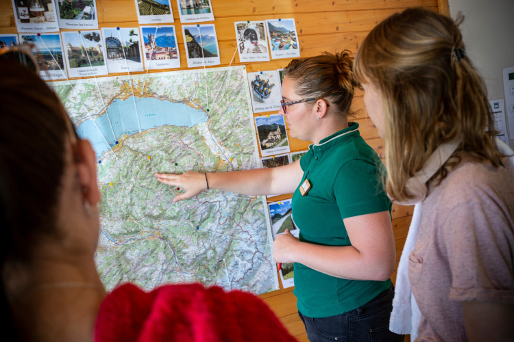 A guide at Camping La Pinède - Excenevex, Auvergne-Rhône-Alpes, France, shows a map to visitors.