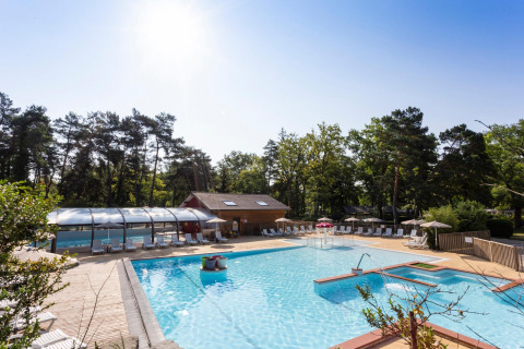 Piscina exterior y zona de descanso en Camping La Pinède - Excenevex, parque vacacional en Auvergne-Rhône-Alpes, Francia.