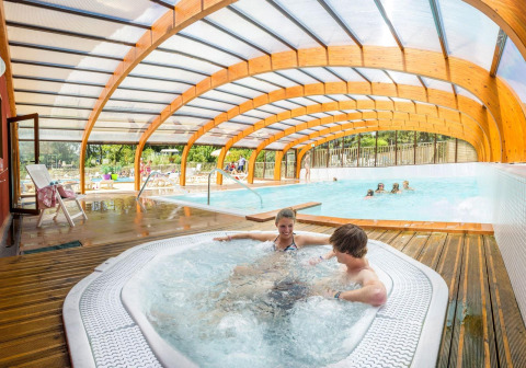 Overdekt zwembad met jacuzzi en gezinnen, Camping La Pinède - Excenevex, Auvergne-Rhône-Alpes, Frankrijk.