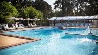 Piscina exterior con tumbonas y sombrillas en Camping La Pinède, Excenevex, Auvergne-Rhône-Alpes, Francia.