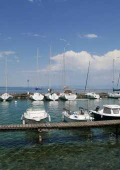 Veleros y barcos atracados en Camping La Pinède - Excenevex en Auvergne-Rhône-Alpes, Francia, con fondo azul.