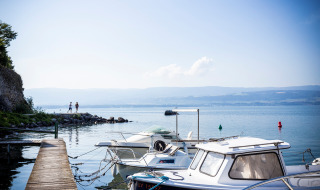 Barcos amarrados en un muelle de Excenevex-Plage, Francia, con vistas al lago y las montañas.