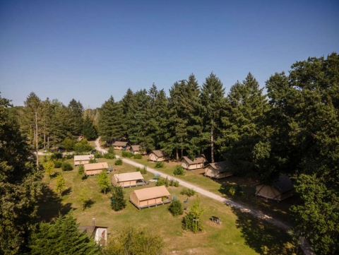 Vista aérea del parque vacacional Huttopia Les Châteaux con tiendas y bosque en Centre-Val de Loire, Francia.