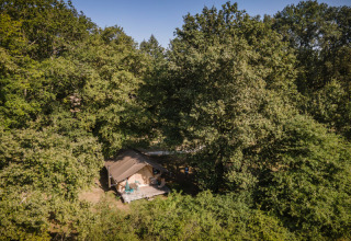 Luftfoto af et glampingtelt omgivet af tæt skov ved Huttopia Les Châteaux i Centre-Val de Loire, Frankrig.
