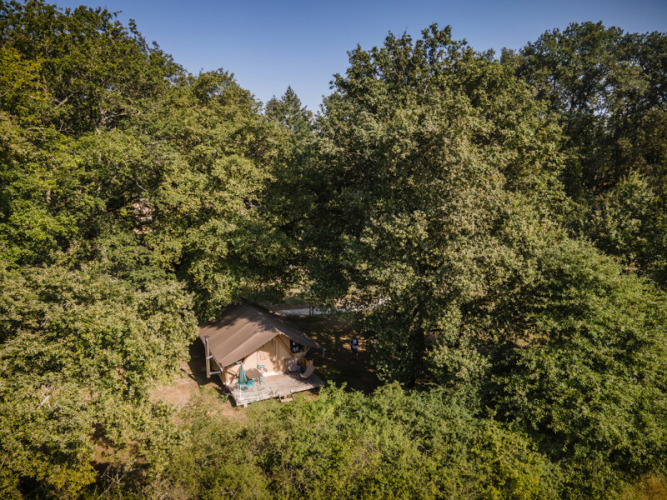 Vue aérienne d’une tente de glamping entourée de forêt dense à Huttopia Les Châteaux, Centre-Val de Loire, France.