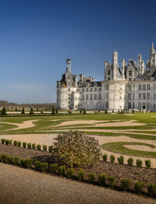 El Castillo de Chambord rodeado de jardines simétricos y césped en un día soleado en el Valle del Loira, Francia.