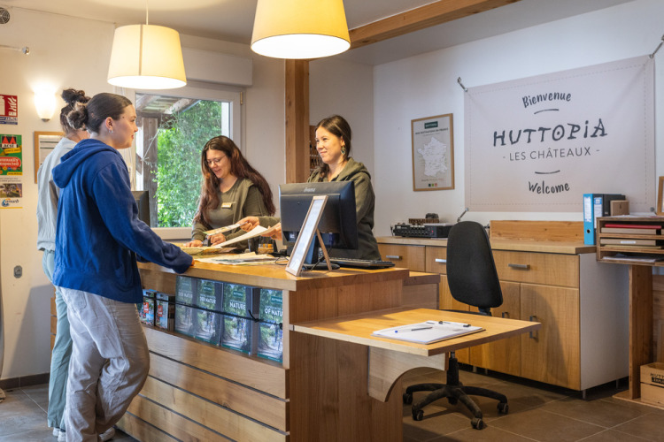 Receptionistes helpen gasten bij het inchecken in Huttopia Les Châteaux vakantiepark in Centre-Val de Loire, Frankrijk.