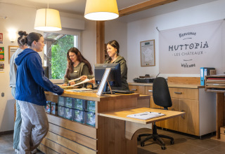 Receptionister hjælper gæster med check-in på Huttopia Les Châteaux feriepark i Centre-Val de Loire, Frankrig.