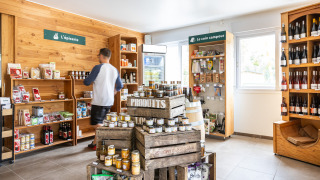 Una pequeña tienda en Huttopia Les Châteaux, Centre-Val de Loire, con estantes llenos de productos locales.