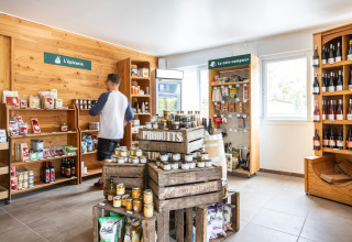 Una pequeña tienda en Huttopia Les Châteaux, Centre-Val de Loire, con estantes llenos de productos locales.