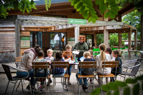 Niños sentados alrededor de una mesa al aire libre en Huttopia Les Châteaux, Centre-Val de Loire, Francia.