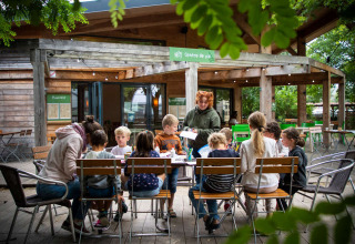 Børn sidder omkring et bord ved udendørs café i Huttopia Les Châteaux, Centre-Val de Loire, Frankrig.
