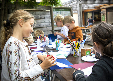 Niños disfrutan manualidades y dibujo al aire libre en un parque vacacional en Centre-Val de Loire, Francia.