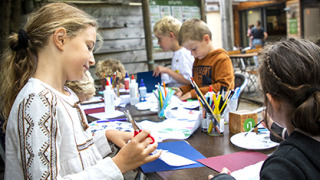 Niños disfrutan manualidades y dibujo al aire libre en un parque vacacional en Centre-Val de Loire, Francia.