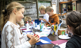 Niños disfrutan manualidades y dibujo al aire libre en un parque vacacional en Centre-Val de Loire, Francia.
